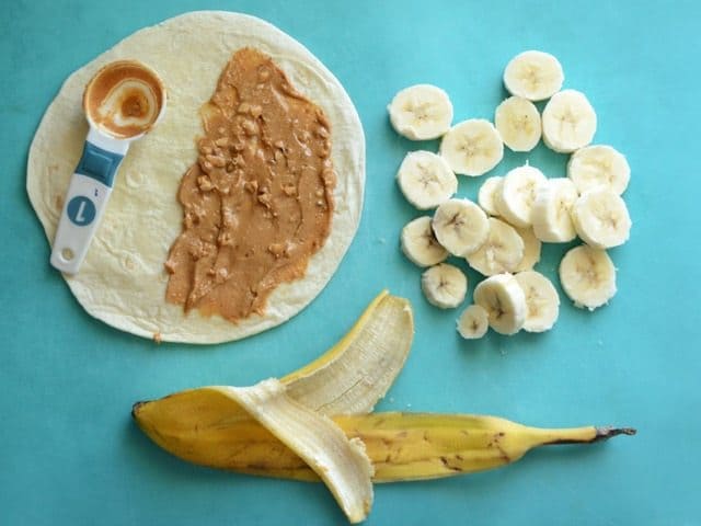 Peanut Butter smeared on a tortilla next to a sliced banana