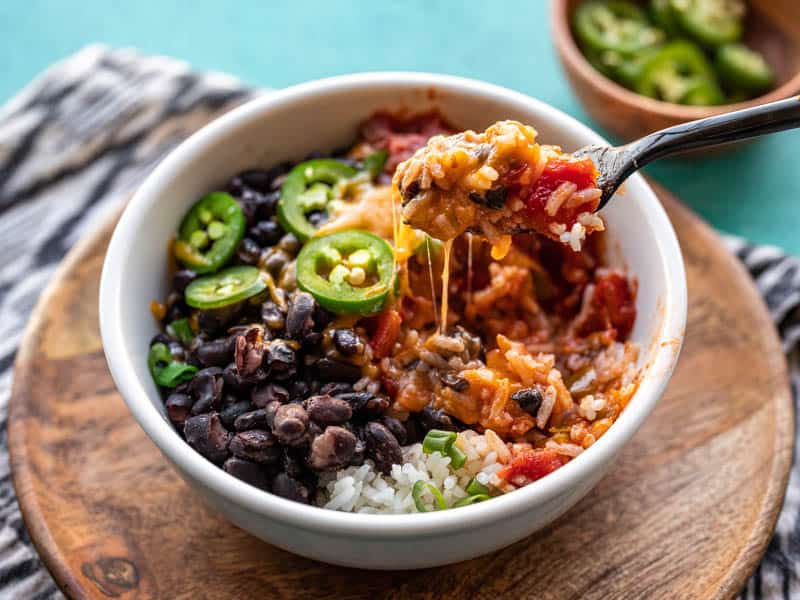 Front view of a Poor Man's Burrito Bowl with a fork lifting a bit out and cheese pulling from the bowl.