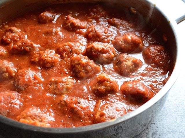 Close up side view of meatballs in the sauce, in the skillet