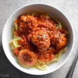 Overhead view of a bowl of pasta with meatballs and marinara