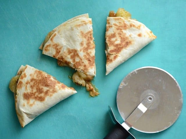 Sliced Caramelized Banana and Peanut Butter Quesadilla next to a pizza cutter