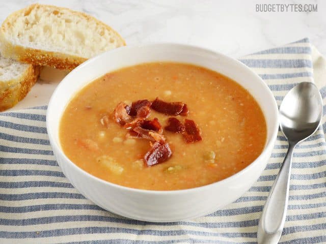 Side view of a bowl of Bacon Bean and Potato Soup, topped with bacon