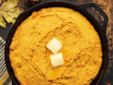 Sweet potato cornbread in a cast iron skillet with butter on top