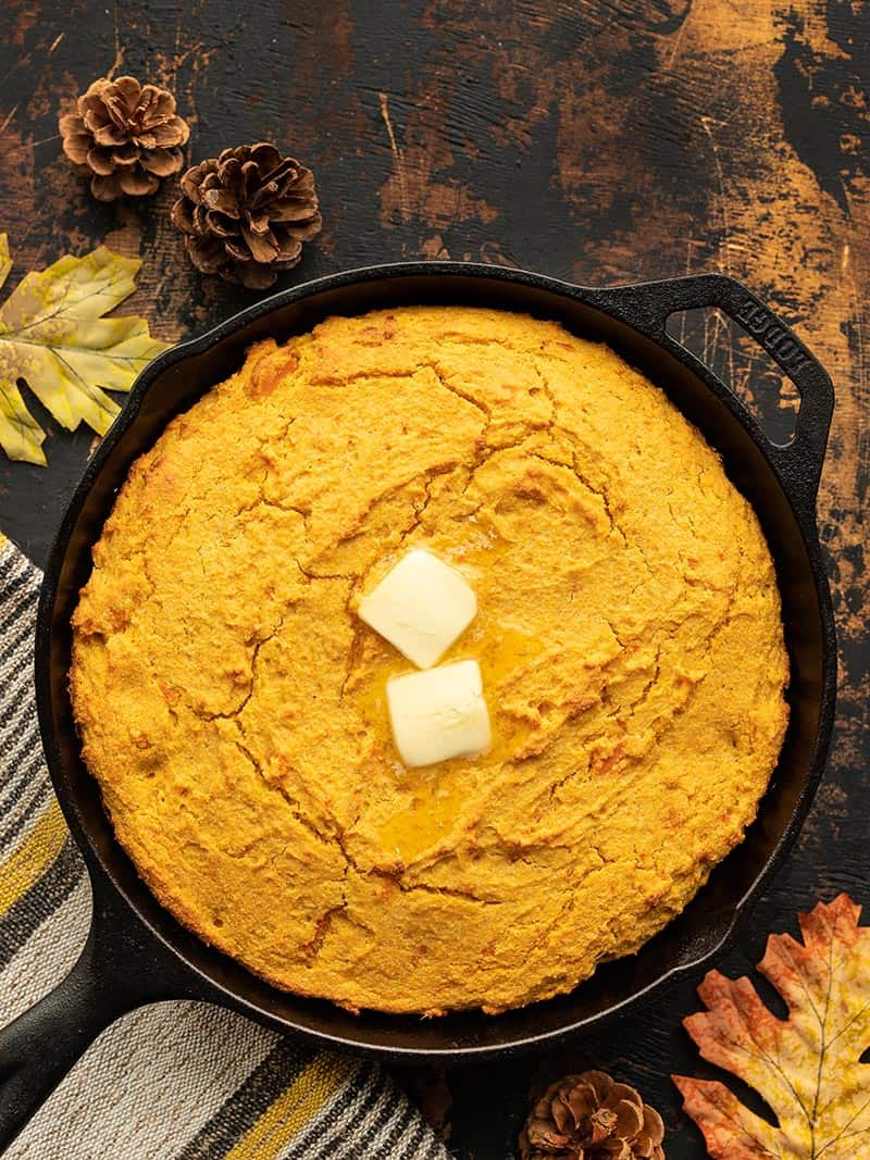 Sweet potato cornbread in a cast iron skillet with butter on top