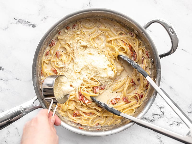 Grated Parmesan being sprinkled over the skillet