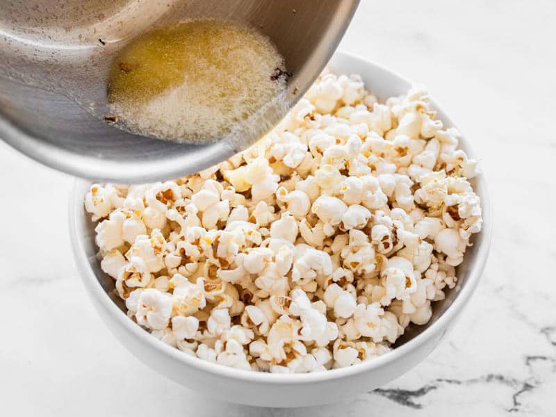 Melted butter being poured onto popcorn