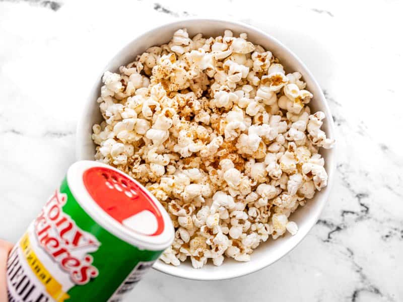 Sprinkle seasoning salt onto buttered popcorn.