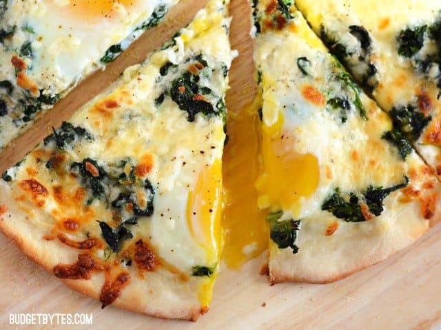 Close up of a few slices of Eggs Florentine Breakfast Pizza with the yolk dripping