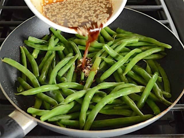 Marinade poured over green beans in the skillet