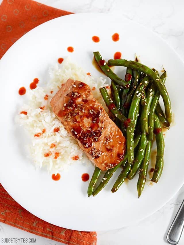 Sesame Glazed Salmon and Green Beans plated with jasmine rice and sriracha