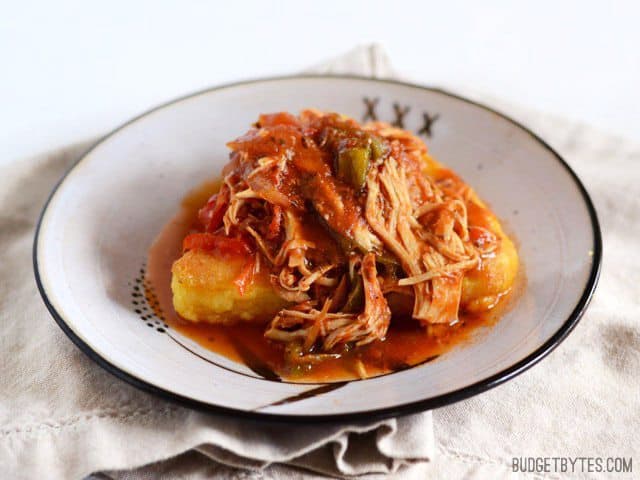 Slow Cooker Italian Chicken and Peppers spooned over a slice of polenta on a plate