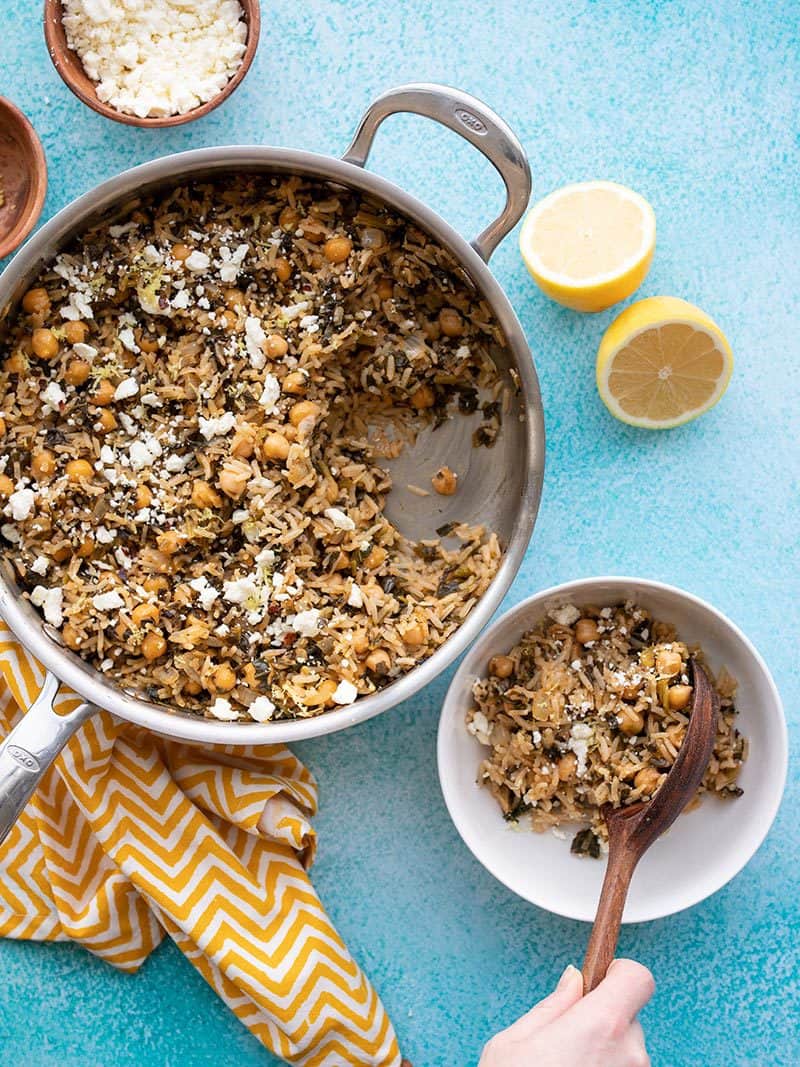 Spinach and Chickpea Rice Pilaf being served into a bowl from the skillet