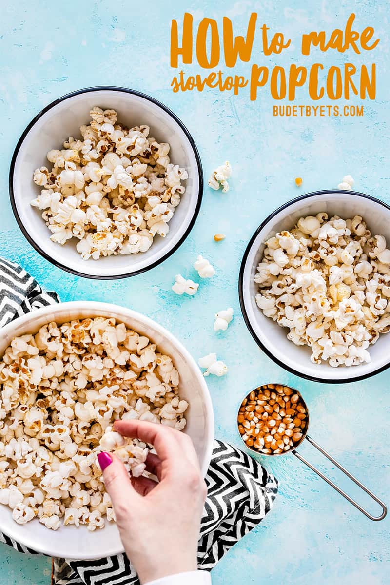 Three bowls of popcorn with a hand grabbing a handful out of one