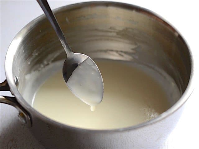 Thickened Sauce dripping off a spoon into the sauce pot