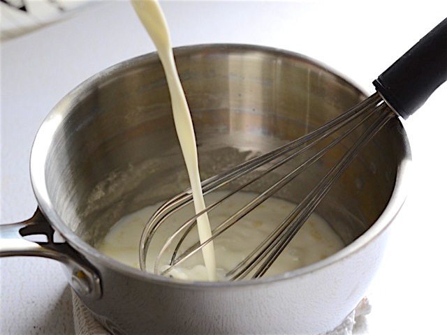 Milk being poured into butter and flour