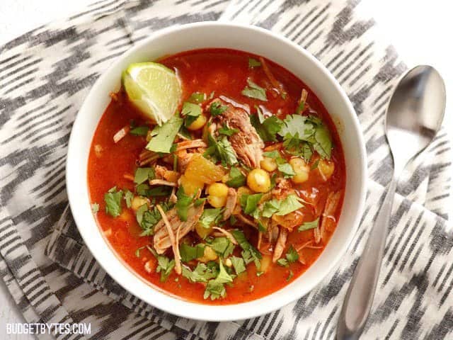 A prepared bowl of 30 Minute Posole with lime and cilantro on a black and white napkin.