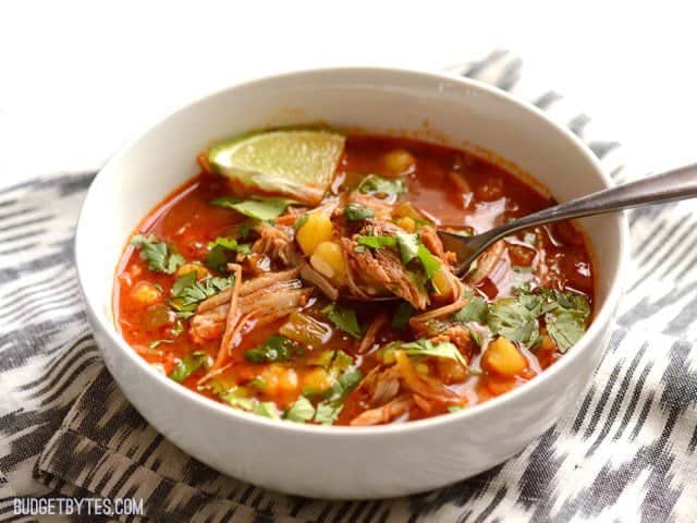 Front view of 30 Minute Posole with a spoon full of pork and hominy. 