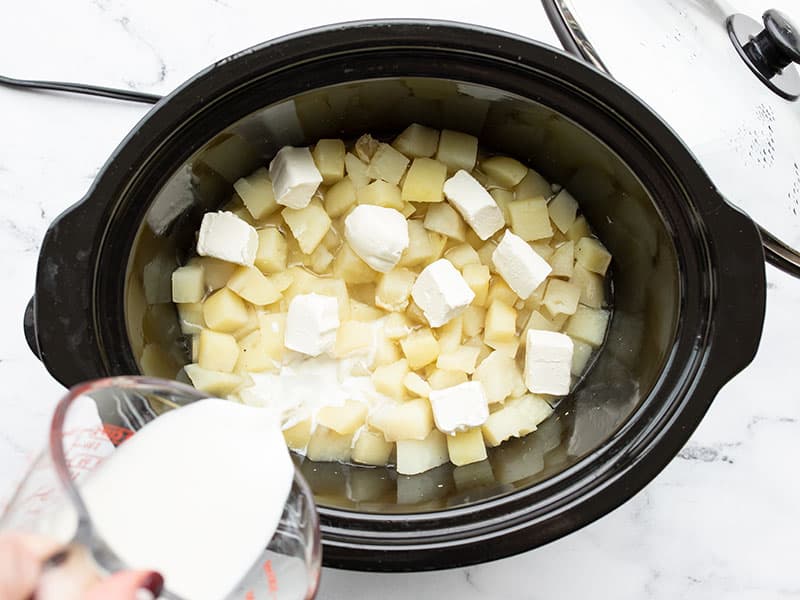 Cream cheese and milk added to the potatoes in the slow cooker