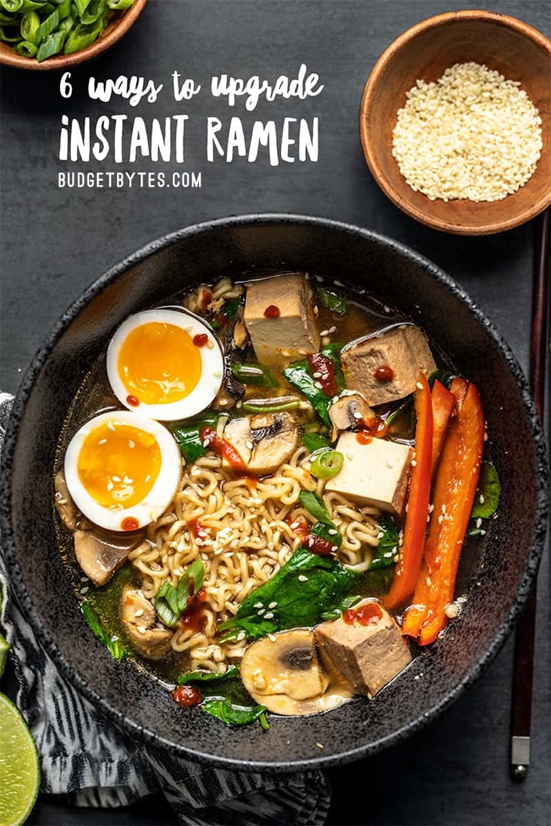 A bowl of upgraded instant ramen with vegetables, soft boiled egg, and sriracha. Limes on the side.