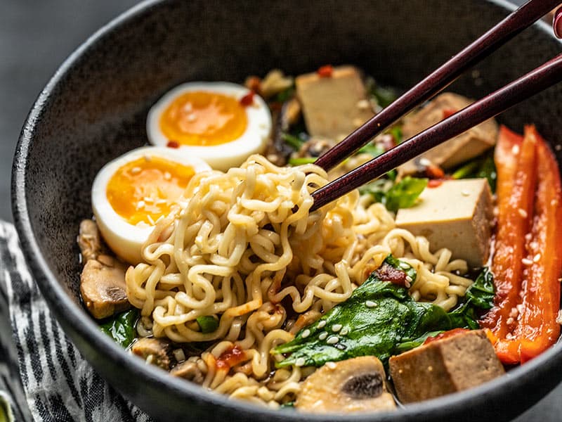 A clump of noodles being lifted out of the bowl of upgraded ramen with chopsticks.