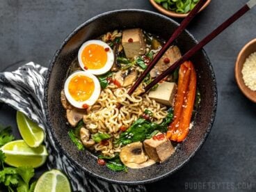 An upgraded bowl of instant ramen, viewed from above, being eaten with chopsticks