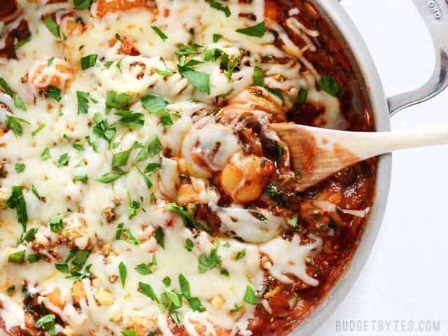 Close up of Cheesy Gnocchi Skillet with a wooden spoon scooping some out of the side