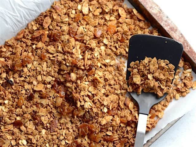Finished gingersnap granola on the baking sheet with a spatula