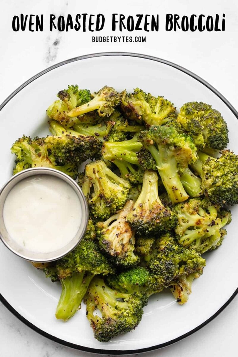 Oven roasted frozen broccoli on a plate with a dish of ranch dressing