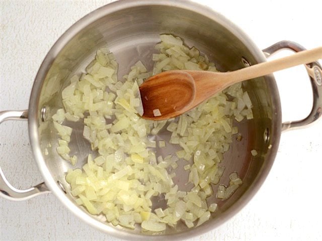 Onion sautéed in oil, in a soup pot with wooden spoon