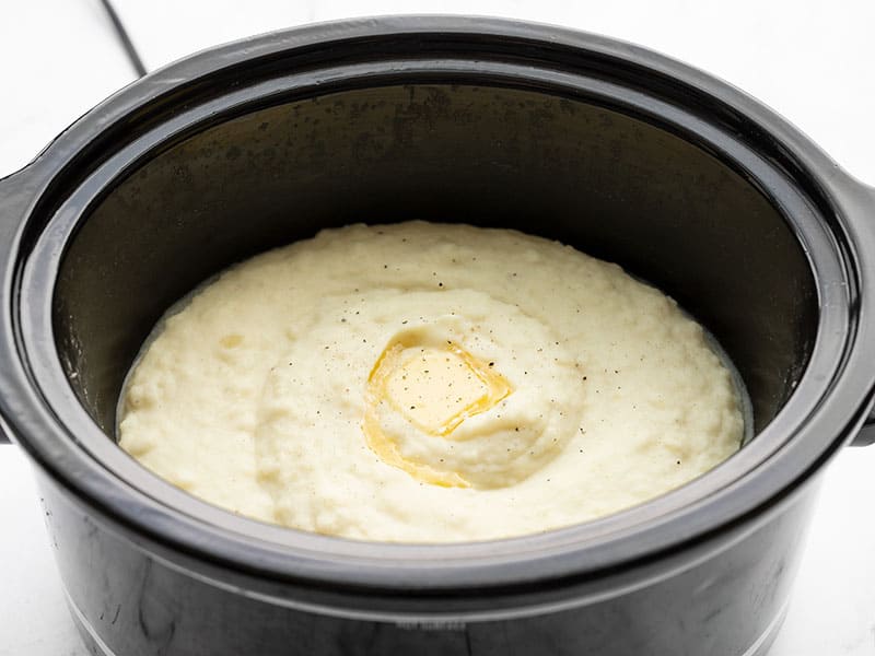 Side view of mashed potatoes in the slow cooker with melted butter