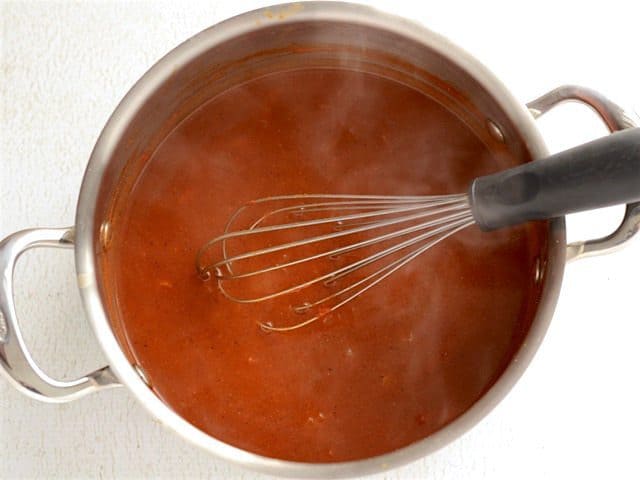 Thickened Enchilada Sauce in the soup pot with a whisk