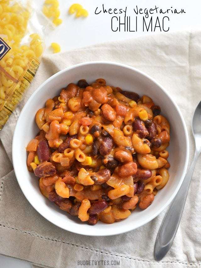 Overhead view of a bowl full of one pot vegetarian chili mac and cheese, a bag of pasta on the side