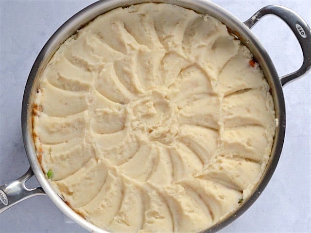 Mashed potatoes topped skillet, design pressed into potatoes with a spoon