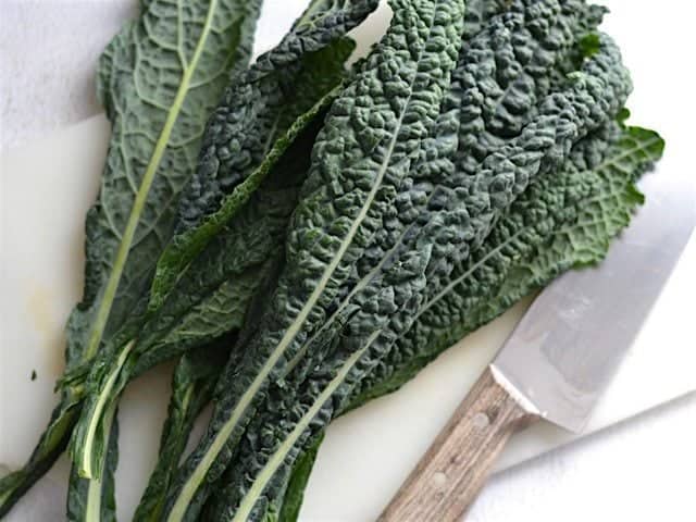 Lacinato Kale on a cutting board next to a knife