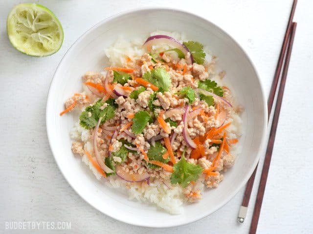 Overhead view of a bowl with nam sod, chopsticks on the side, and a squeezed lime next to the bowl