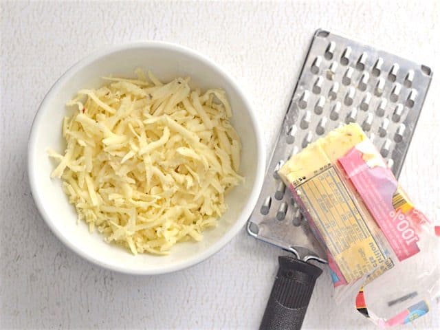 Cheese being shredded into a bowl