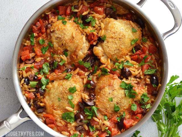 Overhead view of finished one skillet chicken and orzo with olives, garnished with parsley