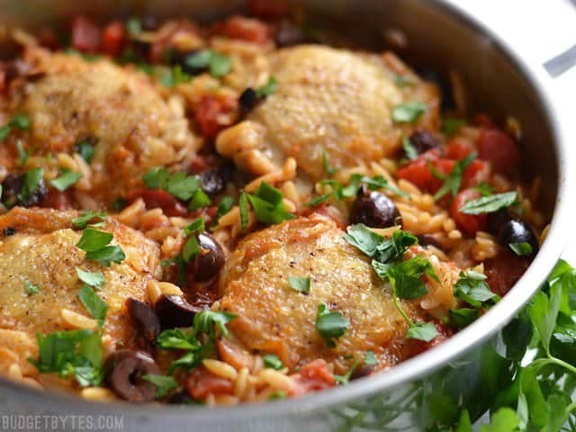 Close up side view of Chicken with Orzo and Olives in the skillet, garnished with parsley