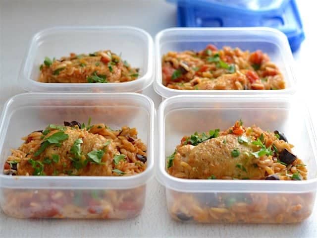 Meal prepped chicken with orzo and olives in square Ziploc containers.