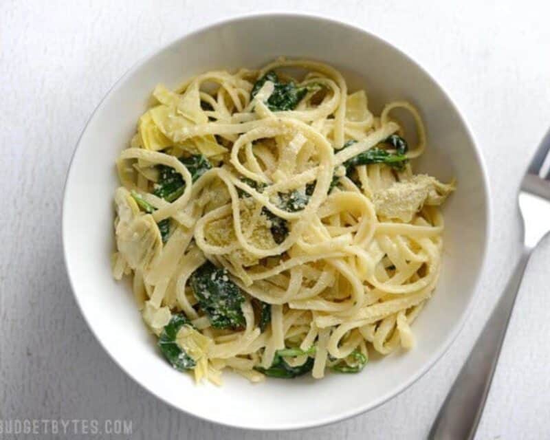 Creamy Spinach Artichoke Pasta is an easy one-pot weeknight dinner made with pantry staples, perfect for Meatless Monday! Budetbytes.com Overhead view of a bowl full of one pot creamy spinach artichoke pasta.