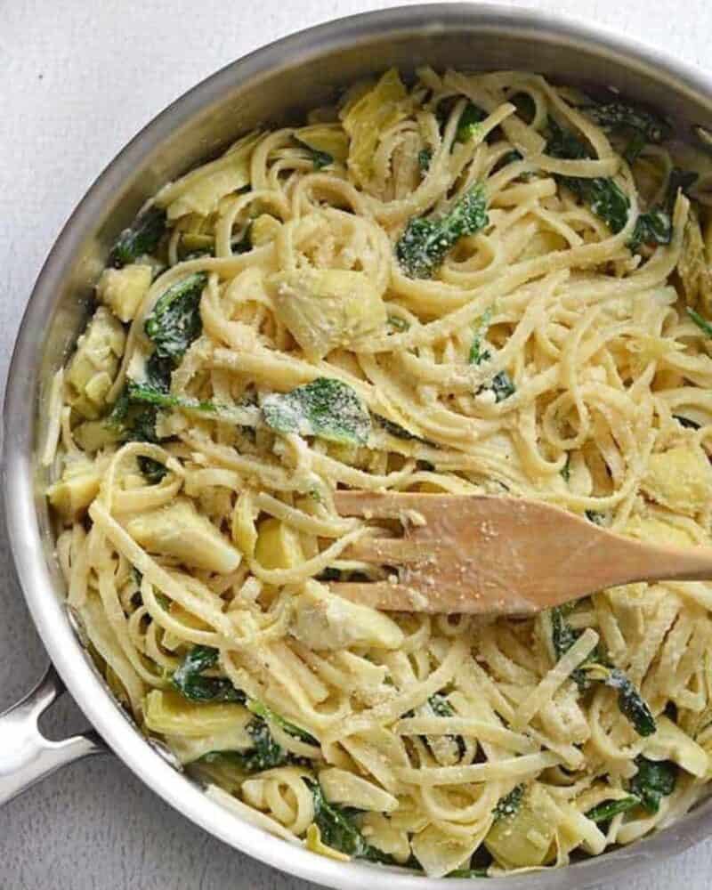 Creamy Spinach Artichoke Pasta is an easy one-pot weeknight dinner made with pantry staples, perfect for Meatless Monday! Budetbytes.com Creamy Spinach Artichoke Pasta in a pot with a wooden spoon.