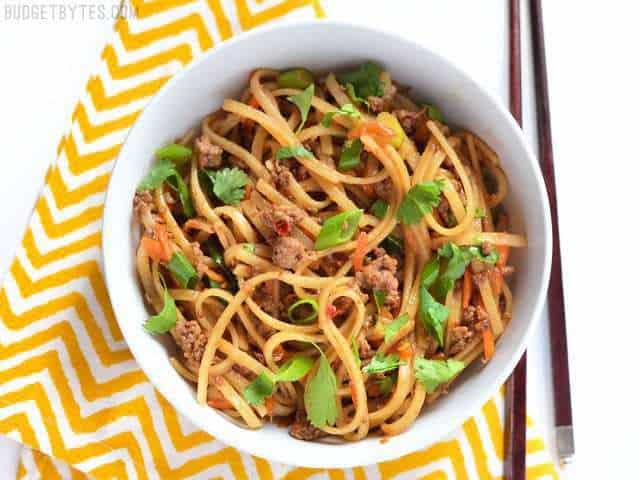 Beef Stir Fry Noodles served in a bowl on a yellow napkin, chopsticks on the side