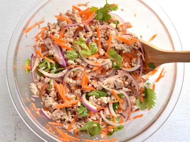 Tossed salad in glass bowl with a wooden spoon