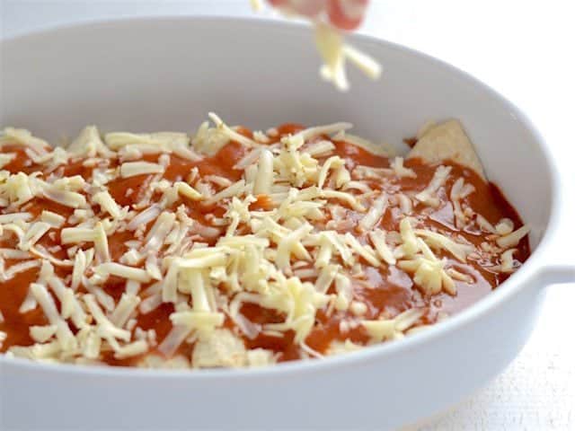 Enchiladas being topped with cheese