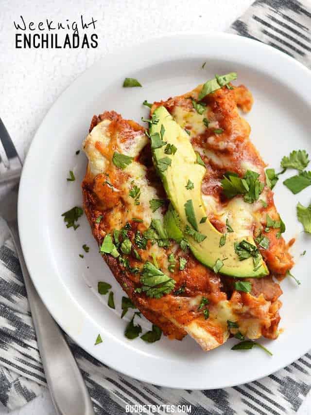 Two Weeknight Bean and Cheese Enchiladas on a plate, garnished with avocado and cilantro.