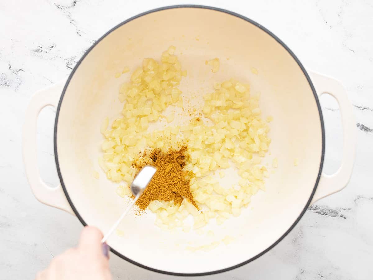 curry powder being added to the soup pot