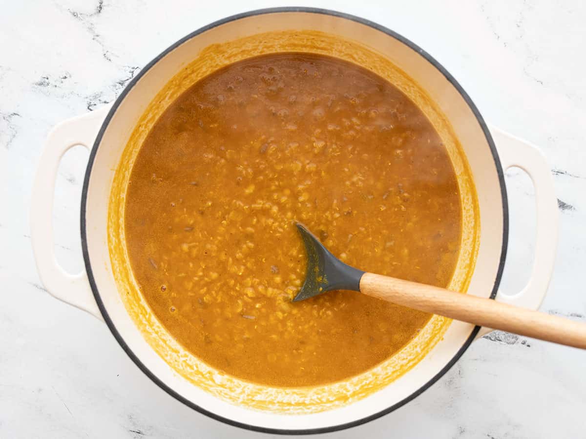 cooked lentil and pumpkin soup in the pot with a spoon