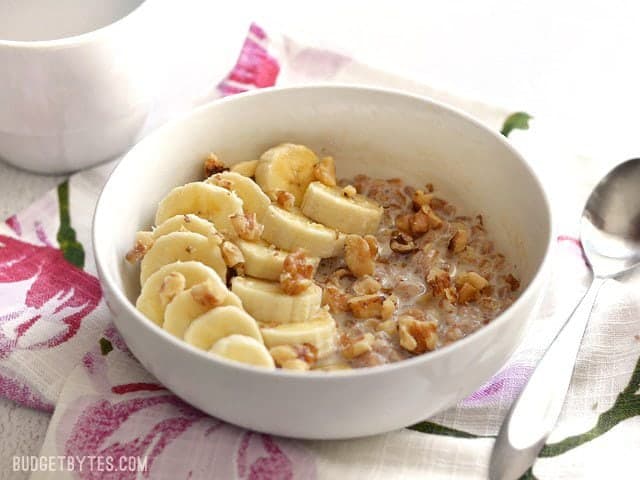 Side view of a bowl of Banana Nut Breakfast Farro topped with sliced banana and chopped walnuts