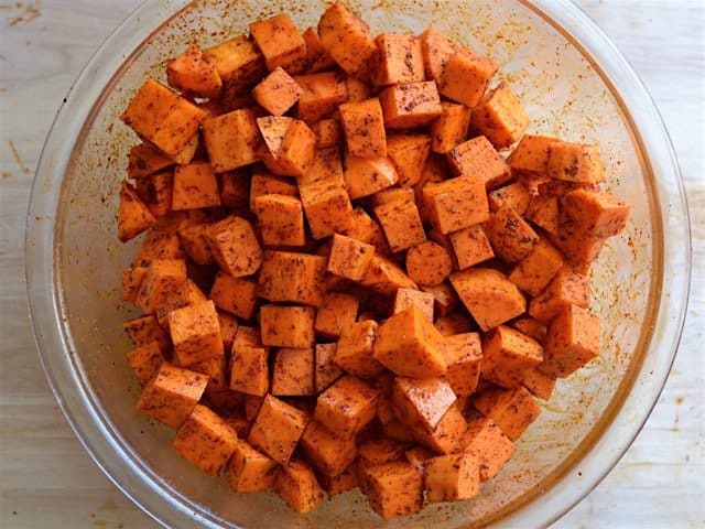 Seasoned sweet potato cubes in a glass bowl