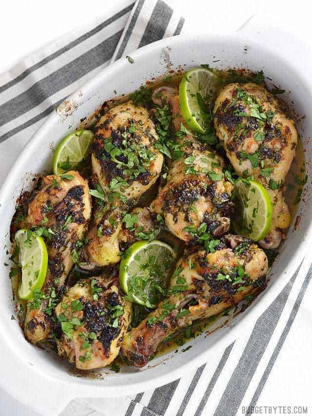 Cilantro Lime Chicken Drumsticks in the baking dish with lime and cilantro